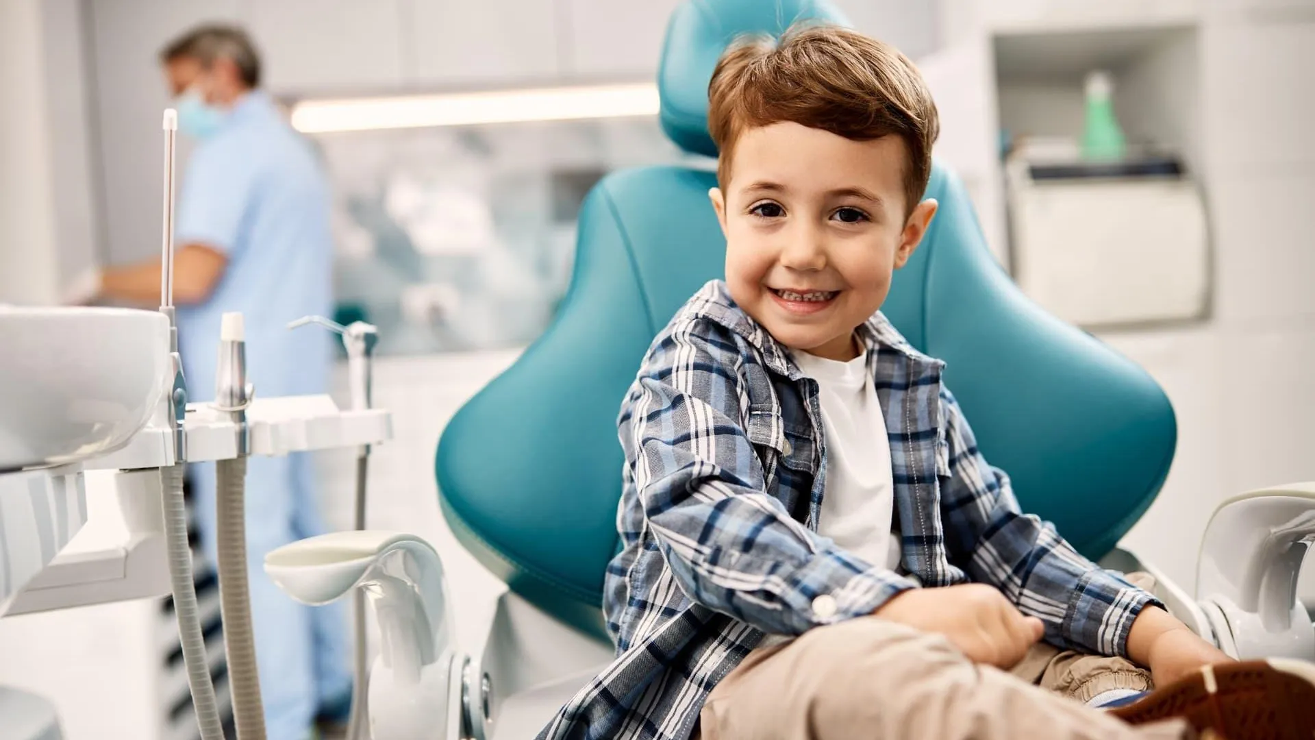 Niño sonriendo sentado en el sillón dental durante una revisión de odontopediatría