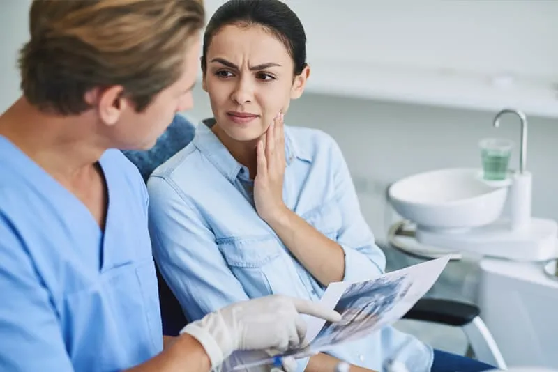 Odontólogo explicando una radiografía dental a una paciente en la consulta